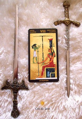 Fotocomposição da carta A Justiça, do Nefertari Tarot, com balança e espada ao fundo.