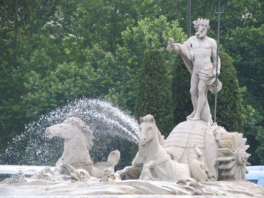 Escultura de Poseidon em uma fonte com cavalos e água.